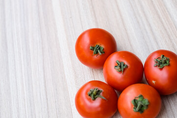 Red tomato on plain wooden table, essential vegetables for all essential foods, view of unpeeled vegetables with plain background