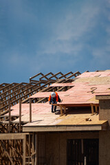 Obraz premium Roofing on rooftop. Builder roofer install new roof. Construction worker roofing on a large roof apartment building development. Roofer carpenter working on roof structure construction site.