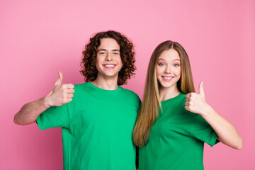 Photo of young cheerful couple teenagers wear green t shirt showing approval in college high school...