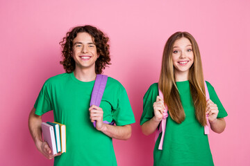 Portrait of happy couple teenagers wear green t shirt bring backpacks and literature to prepare...