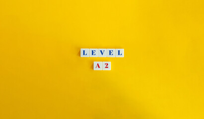 Level A2 Word and Banner. Block Letter Tiles on Yellow Background. Minimalist Aesthetic.
