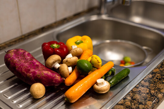 An assortment of washed organic vegetables on draining board by kitchen sink