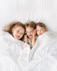 Happy family - portrait of children and mother in bed. Happy, love and fun at home. Family, childhood.
