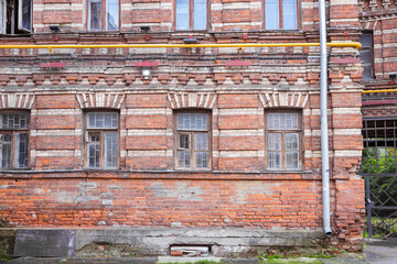 A fragment of the facade of an old brick building with windows.