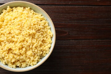 Tasty millet porridge in bowl on wooden table, top view. Space for text