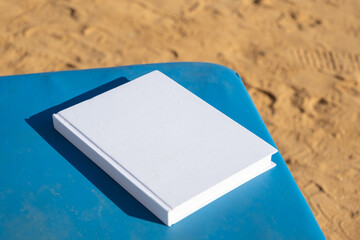 blank book mockup on lounge on sandy beach
