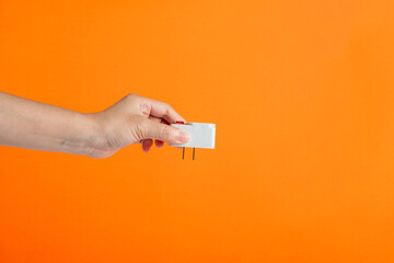Hand with plug isolated on orange background.