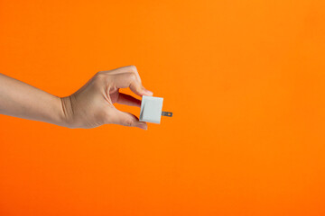 Hand with plug isolated on orange background.