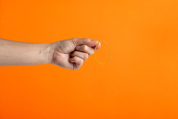 Yellow rubber bands close up with hand isolated on orange background