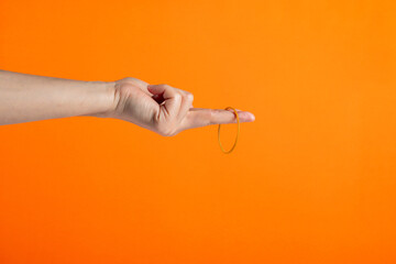 Yellow rubber bands close up with hand isolated on orange background