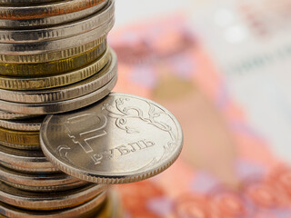 1 ruble coin on the background of a stack of coins and banknotes