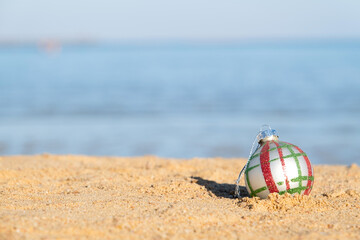 Fototapeta na wymiar Christmas decorations bauble ball on sandy beach with sea background