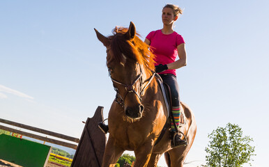 Woman rider rides horse on ranch