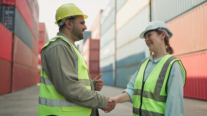 Two industrial engineers man and woman shake hands to celebrate success work together at cargo...