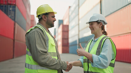 Two industrial engineers man and woman shake hands to celebrate success work together at cargo...