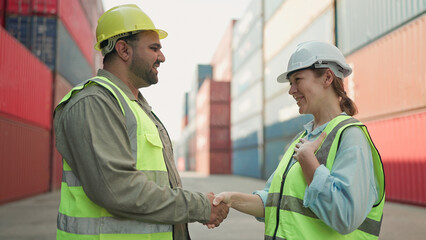 Two industrial engineers man and woman shake hands to celebrate success work together at cargo...