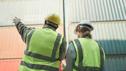 Back view of two industrial engineers man and woman checking container storage with cargo container. Cargo shipping import and export industry. Logistic shipping yard business. Teamwork