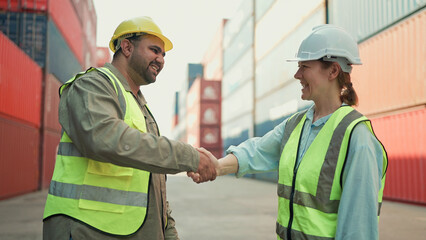 Two industrial engineers man and woman shake hands to celebrate success work together at cargo container yard. Logistic shipping yard business. Teamwork concept