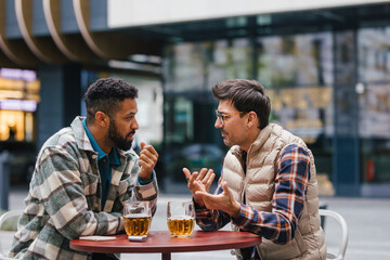 Best friends togehter, drinking beer and talking in bar in city. Concept of male friendship, bromance.