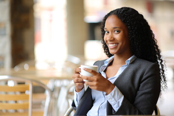 Black businesswoman drinking coffee looking at you