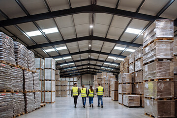 Rear view of warehouse workers walking in warehouse. Team of warehouse workers preparing products...