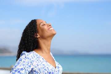 Happy black casual woman breathing on the beach