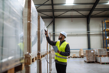 Warehouse worker holding scanner, scanning the barcodes on products in warehouse. Warehouse manager using warehouse scanning system.