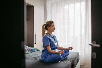 Female nurse or doctor enjoying free time at home after work, meditating. Work-life balance for a...