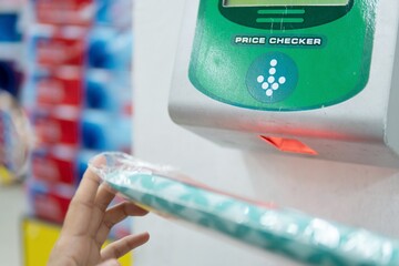 Closeup image of customer using price checker at supermarket.