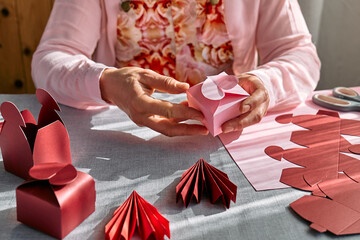 Paper craft diy. Woman's hands making handmade heart shaped gift box for Valentines day, birthday,...