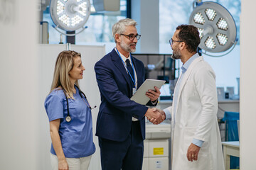 Pharmaceutical sales representative presenting new medication to doctors in medical building,...