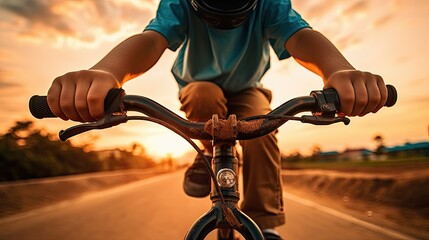 Perspective of a child riding a bicycle at sunset, hands on handlebars.