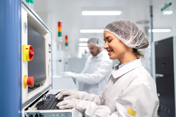 Fototapeta premium Female factory employee working on production line and operating industrial machine.