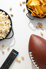 Popcorn and chips with a rugby ball on a light background