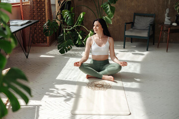 Content female practitioner peacefully performing padmasana in lotus position on cozy yoga rug....