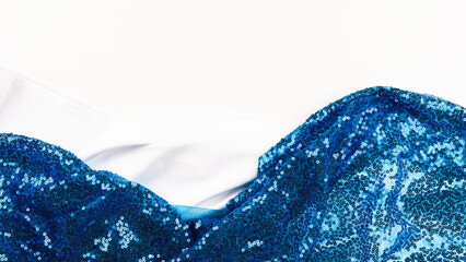 Fashion blog concept. White satin or silk fabric with blue sequins as a background. Glitter texture is the trend of the season. Sparkling color blue. Textured background for atelier.