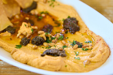 Hummus with olive oil and pine nuts on a white plate