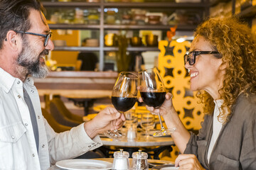Happy couple smiling and talking in a restaurant drinking red wine - Married couple having lunch break at cafe bar - Lifestyle concept with man and a woman going out on weekend day