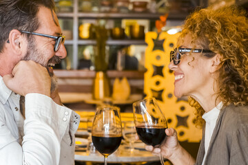Happy couple smiling and talking in a burger pub restaurant - Married couple having lunch break at cafe bar - Lifestyle concept with man and a woman going out on weekend day