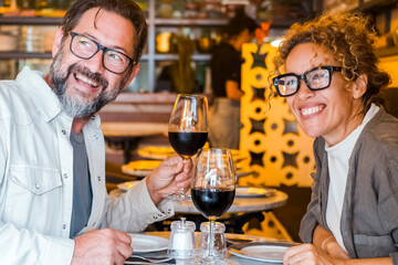 Happy couple smiling and talking in a restaurant drinking red wine - Married couple having lunch break at cafe bar - Lifestyle concept with man and a woman going out on weekend day