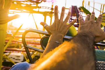 Pov of Couple on a roller coaster with arms in the air amused and excited waiting for the steep...