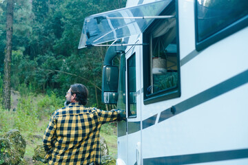 One man enjoying travel destination outside a modern camper van admiring green environment forest...