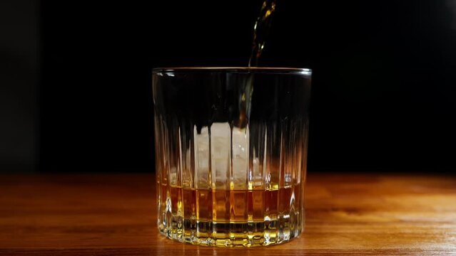 4K Slow Motion Shot of Pouring Whiskey into Glass with Ice Cubes.