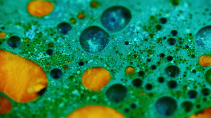 Oil fluid flow. Glitter ink water. Blur green cyan blue golden color sparkling fizz bubble texture liquid wave motion abstract art background.