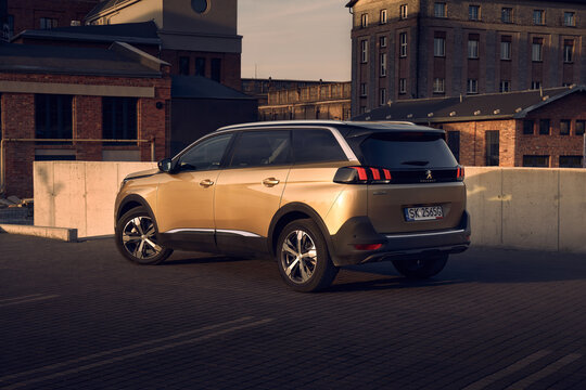 Golden Peugeot 5008, 7 person SUV, in the parking lot in front of old  factory buildings. Katowice, Poland, 06.03.2017