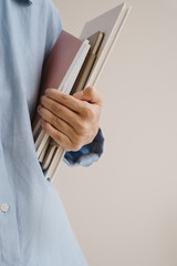 Office documents, notebooks, paper sheets in person's hands. Person in blue linen shirt holds...