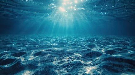 Sunlight pierces the clear blue waters of the ocean, illuminating the tranquil sandy sea floor below. - obrazy, fototapety, plakaty