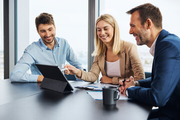 Happy businesswoman discussing over tablet PC with colleagues in office