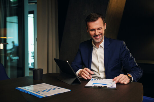 Happy mature businessman analyzing data in conference room