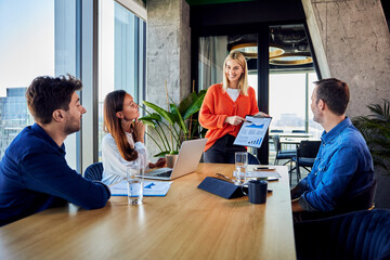 Smiling businesswoman explaining graph to colleagues in office